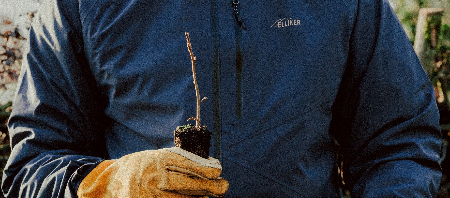 ELLIKER team member holding plant sapling wearing heavy gloves and ELLIKER jacket