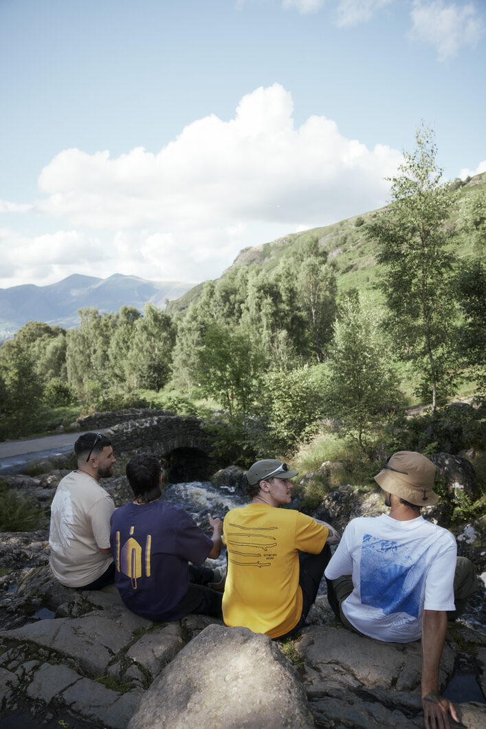 Trail Dusters sitting by stream wearing ELLIKER t-shirts