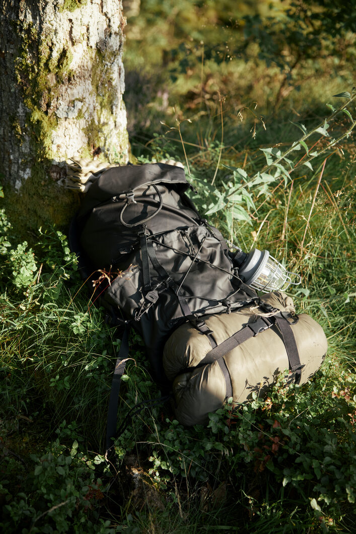 ELLIKER Maller bag in Black resting against mossy tree