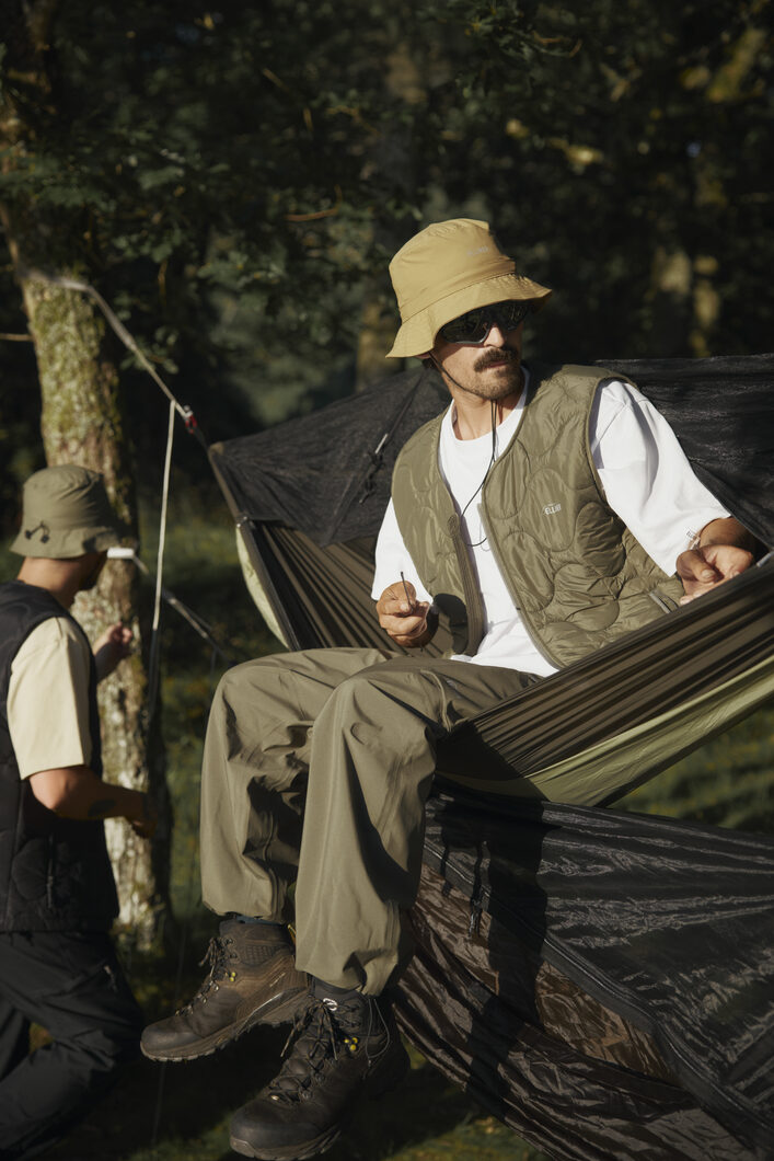 Sitting in hammock wearing ELLIKER Burter Bucket Hat, Satron Insulated Vest and Bordley Shell Trousers